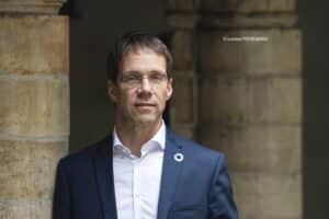 Benoiy Derenne portant une chemise blanche et une veste de costume bleu marine