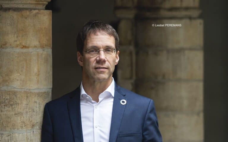 Benoiy Derenne portant une chemise blanche et une veste de costume bleu marine
