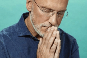 Photo d'un homme qui prie les mains devant sa bouche et les yeux fermés