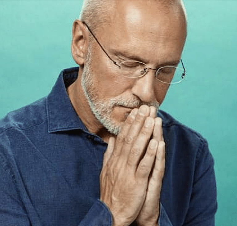 Photo d'un homme qui prie les mains devant sa bouche et les yeux fermés