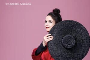 Photographie portrait d'Amélie Nothomb cachant son épaule avec un gros chapeau de paille noir