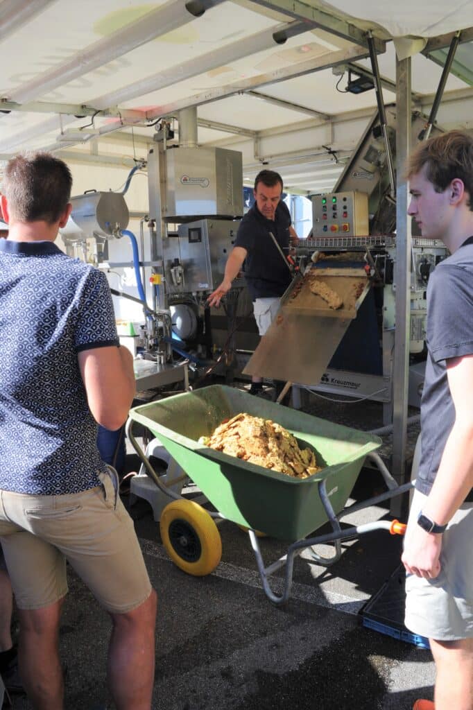 Plusieurs hommes sont autour d'une brouette dans laquelle les restes des pommes sont entassés pour les recycler