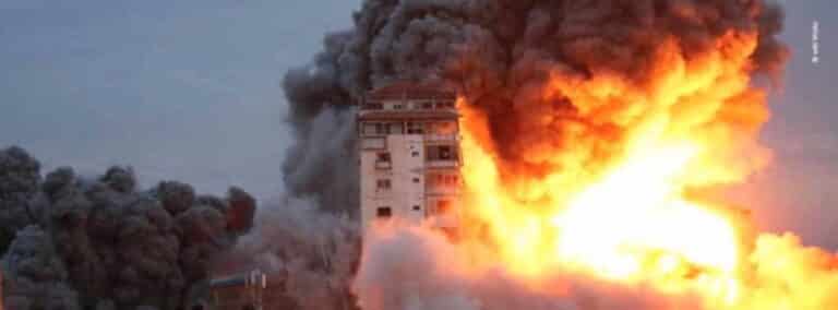 Photo d'un bâtiment avec une explosion autour, de la fumée noire et du feu