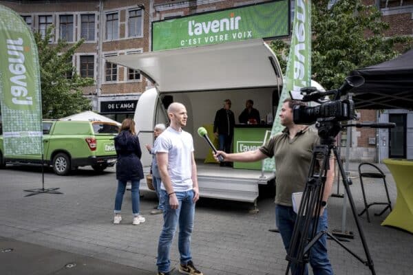 Un journaliste de L'Avenir tendant le micro à un homme dans la rue.