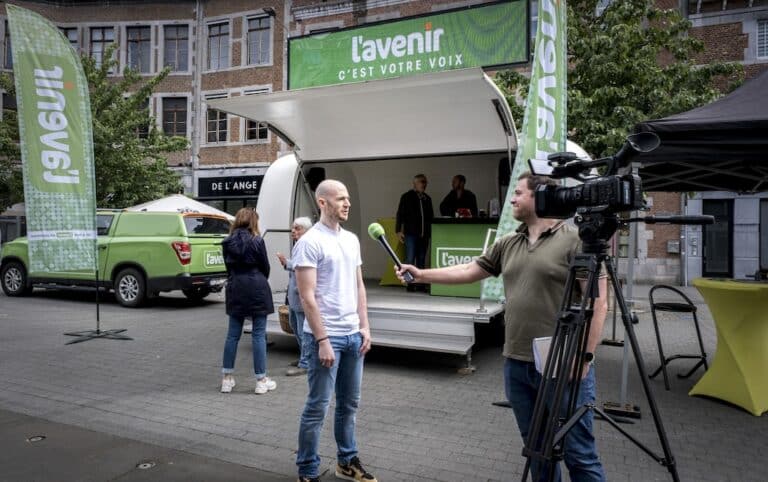 Un journaliste de L'Avenir tendant le micro à un homme dans la rue.