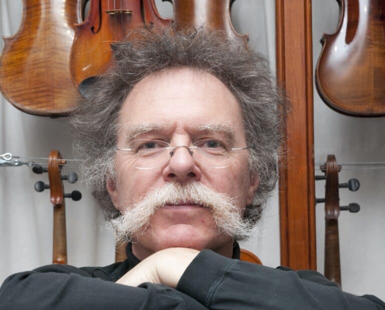 Photo du luthier Gauthier Louppe dans sa boutique devant plusieurs violons