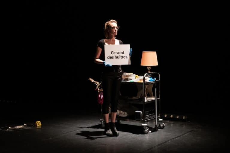 Comédienne sur la scène portant une affiche où il est indiqué "ce sont des huitres"