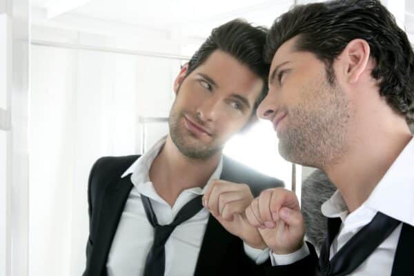 Un jeune homme narcissique en costume se regarde dans le miroir