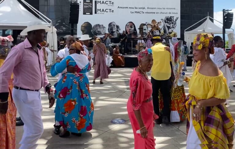 Des Guadeloupéens dansent et font la fête sur une place avec des tenues colorées