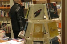 Un homme dans une librairie regardant des livres posés sur une étagère