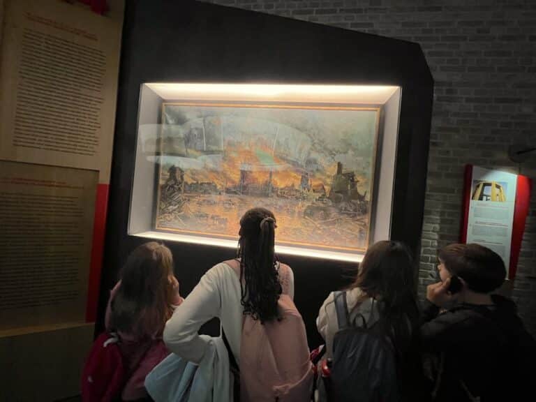 Quatre enfants, de dos, regardent une toile accrochée contre un mur