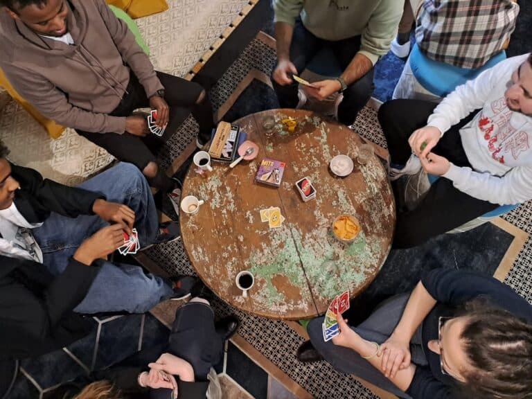 Plusieurs personnes assises autour d'une table sur laquelle il y a des cartes et des boissons dessus