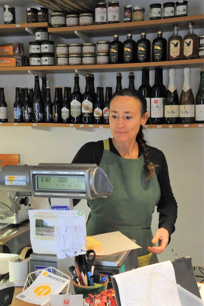 Laurence Votquenne derrière son comptoir qui pèse une tranche de fromage
