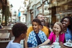 Image représentant une famille à table sur la terrasse d'un café en train de rigoler