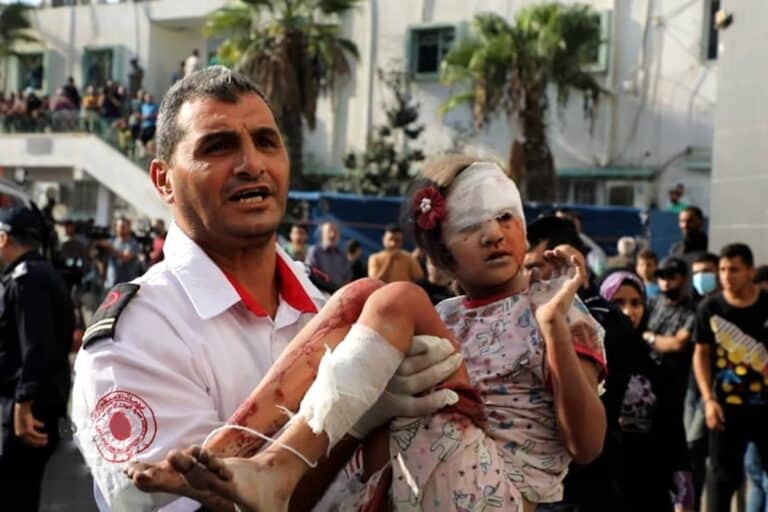 Un soldat palestinien tenant dans ses bras une fillette blessée avec des bandages autour de la jambe et de la tête