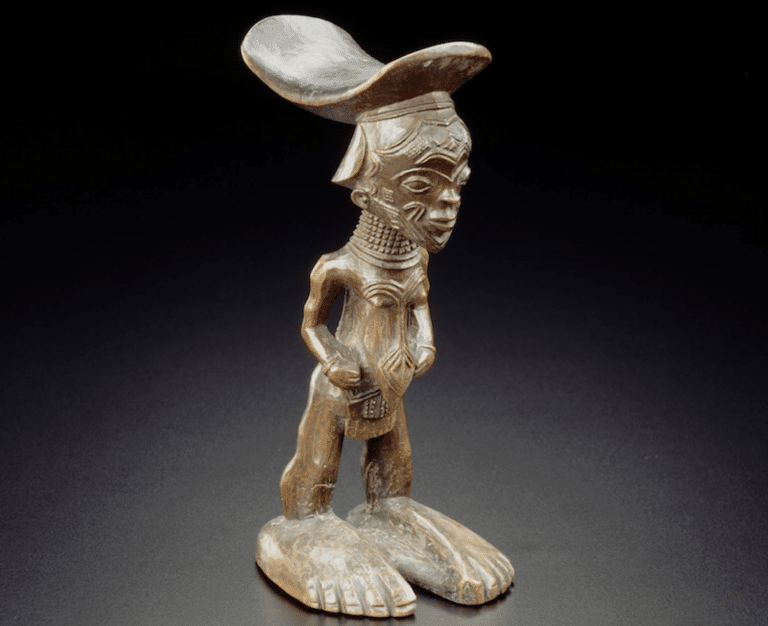 Petite statuette représentant un un homme aux grands pieds avec quelque chose sur la tête