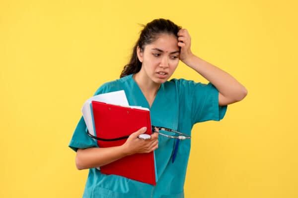 Une infirmière tenant une farde et un stéthoscope, la main sur la tête