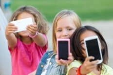 3 enfants qui tiennent un téléphone devant leur visage