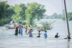 Plusieurs hommes sont dans l'eau, chacun tient une corde qui les relie, durant une période d'inondation