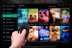 Une main qui tient une télécommande devant l'écran d'un catalogue VOD