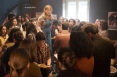 Une femme debout sur une chaise avec des gens autour d'elle