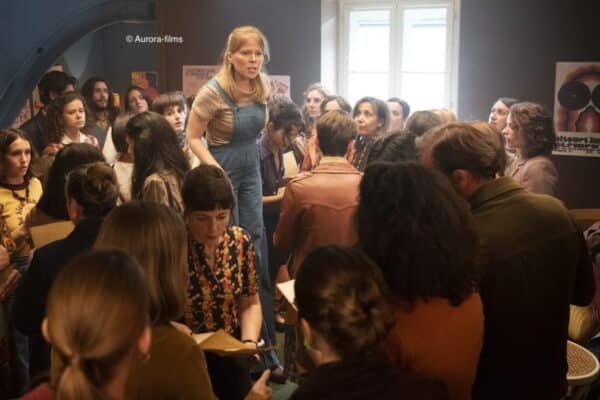 Une femme debout sur une chaise avec des gens autour d'elle