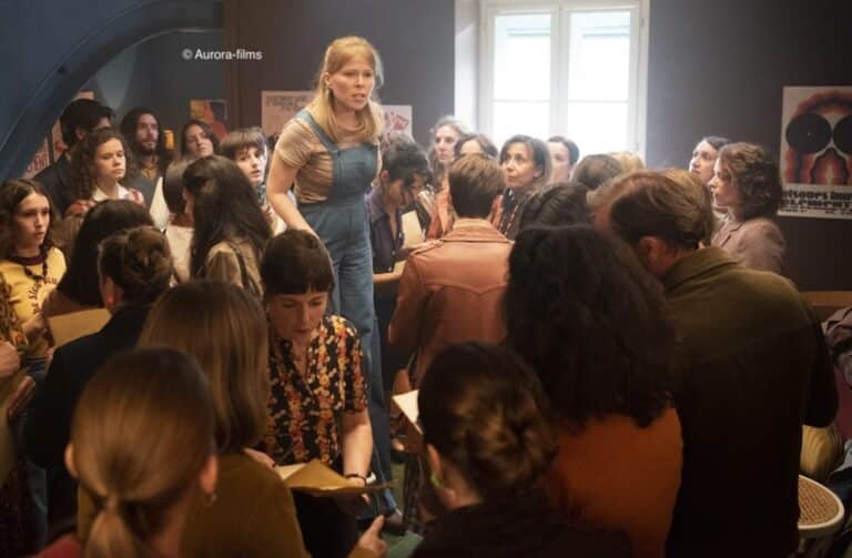 Une femme debout sur une chaise avec des gens autour d'elle