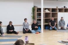 Plusieurs personnes assises par terre dans une salle avec du parquet clair