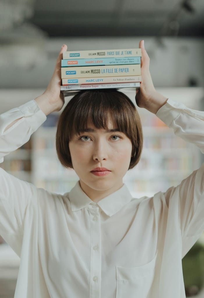 Une femme portant une pile de livre au dessus de la tête