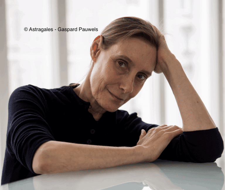 Photo de Michèle Anne de Mey accoudée sur une table en verre