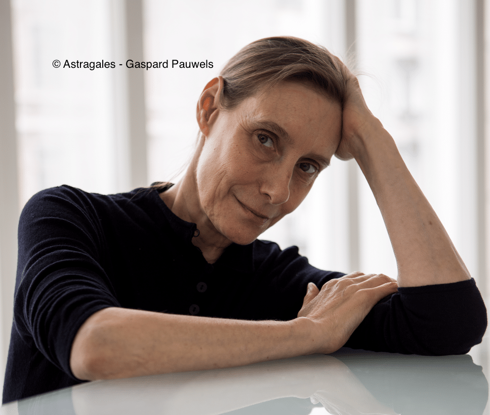 Photo de Michèle Anne de Mey accoudée sur une table en verre
