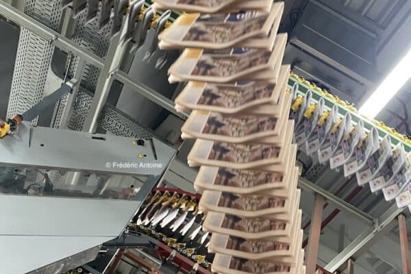 Plusieurs journaux papiers imprimés pendus à des machines qui servent à les imprimer