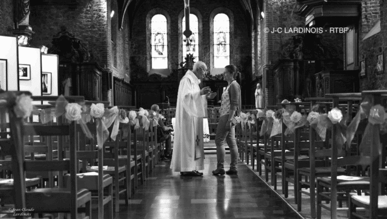 Intérieur d'une église avec un prêtre parlant avec une femme