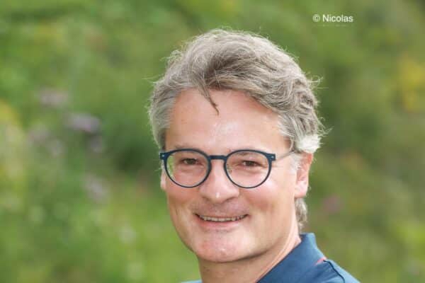 Portrait de Nicolas Monseu souriant avec de l'herbe derrière lui