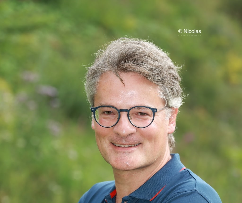Portrait de Nicolas Monseu souriant avec de l'herbe derrière lui