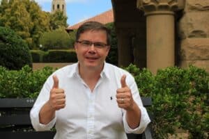 Gregory Renard dans un jardin, souriant, les pouces levés