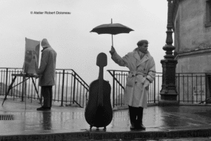 Un homme sous la pluie dehors tenant un parapluie avec un instrument de musique à côté de lui