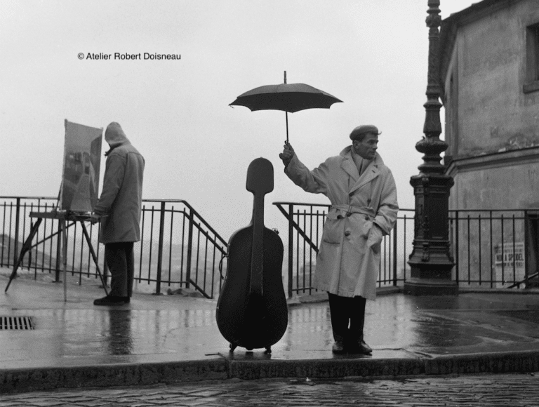 Un homme sous la pluie dehors tenant un parapluie avec un instrument de musique à côté de lui