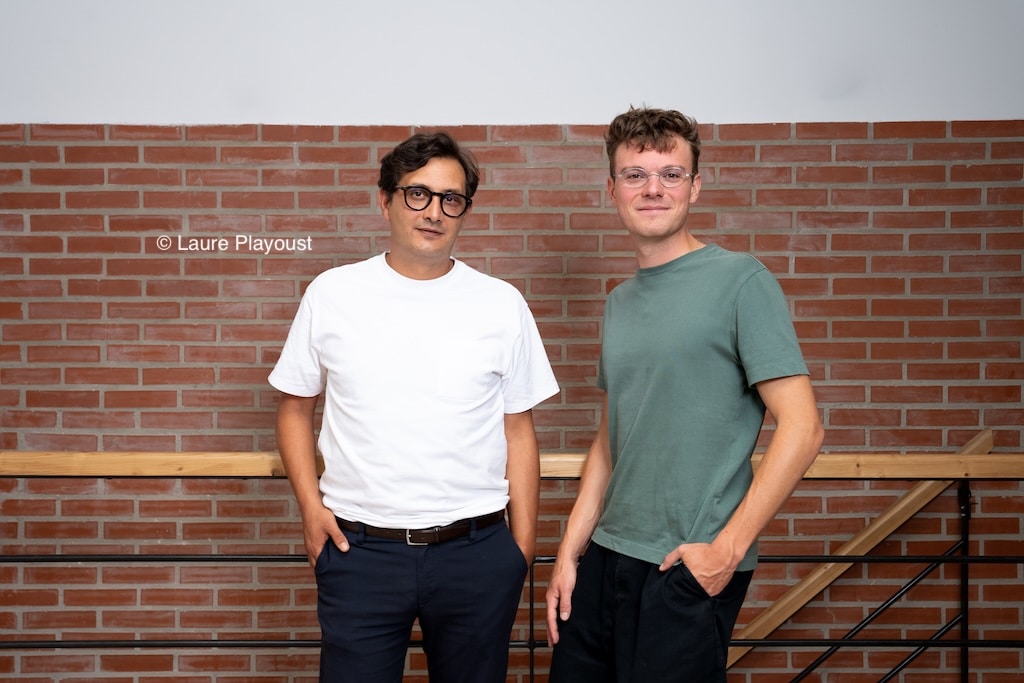 Deux hommes en t-shirt devant un mur de briques