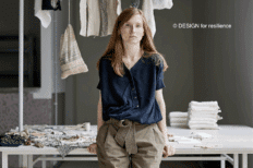 Vanessa Collignon appuyée sur une table et des vêtements accrochés sur un portique