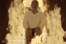 Un homme assis sur une chaise avec des flammes derrière lui