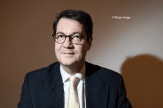 Photo de Bruno Colmant devant un mur uni de couleur brune