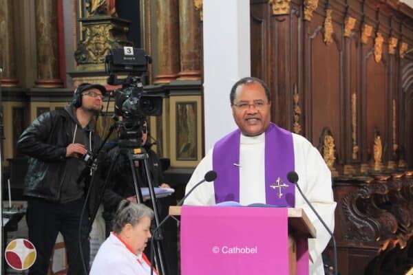 Un prêtre et une caméra derrière lui qui filme la messe