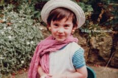 Photo d'un enfant portant des boucles d'oreilles, un chapeau et une écharpe rose