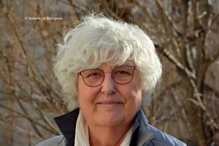 Photo d'Isabelle le Bourgeois à l'extérieur devant des branches d'arbres