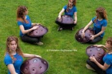 Plusieurs femmes assises dans l'herbe en train de jouer du handpan