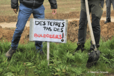 Une pancarte sur laquelle est écrit "des terres, pas des bulldozers"