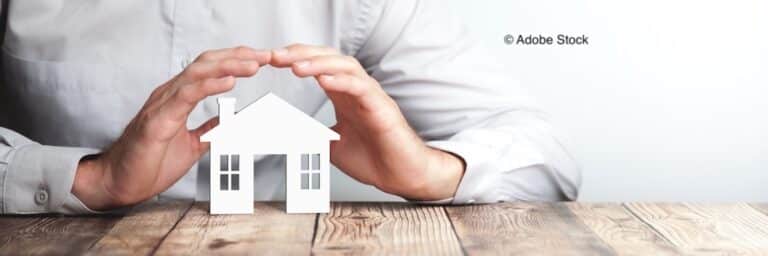 Une petite maisonnette en bois avec des mains autour