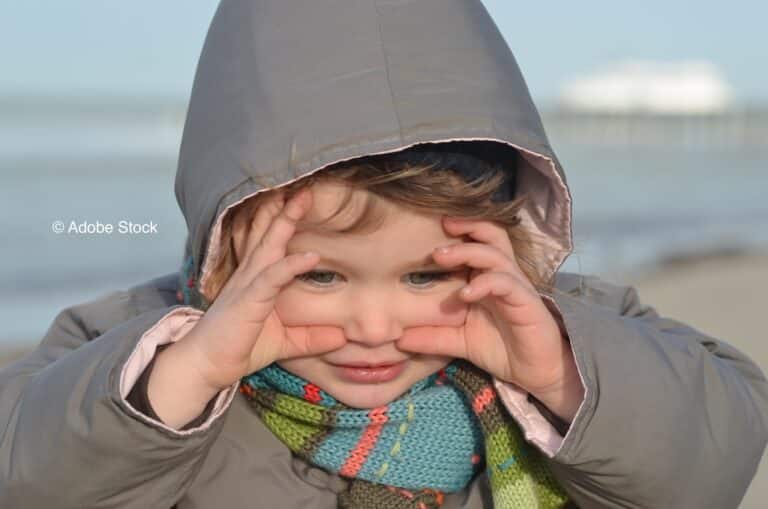 Un enfant avec les mains écartées autour des yeux
