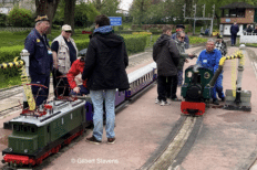 Des petits trains à vapeur et plusieurs personnes autour